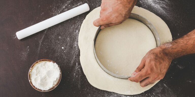 person cutting dough with round cutter