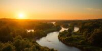 Winding river in a lush green landscape at sunset.