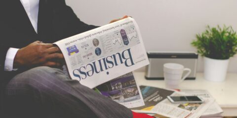 person sitting near table holding newspaper