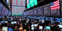 Traders on a crowded stock exchange floor at sunset.