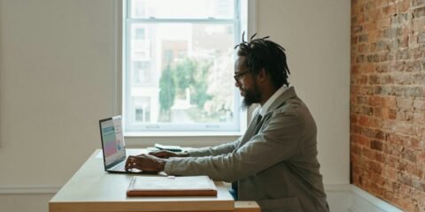 a person sitting at a desk with a laptop and papers