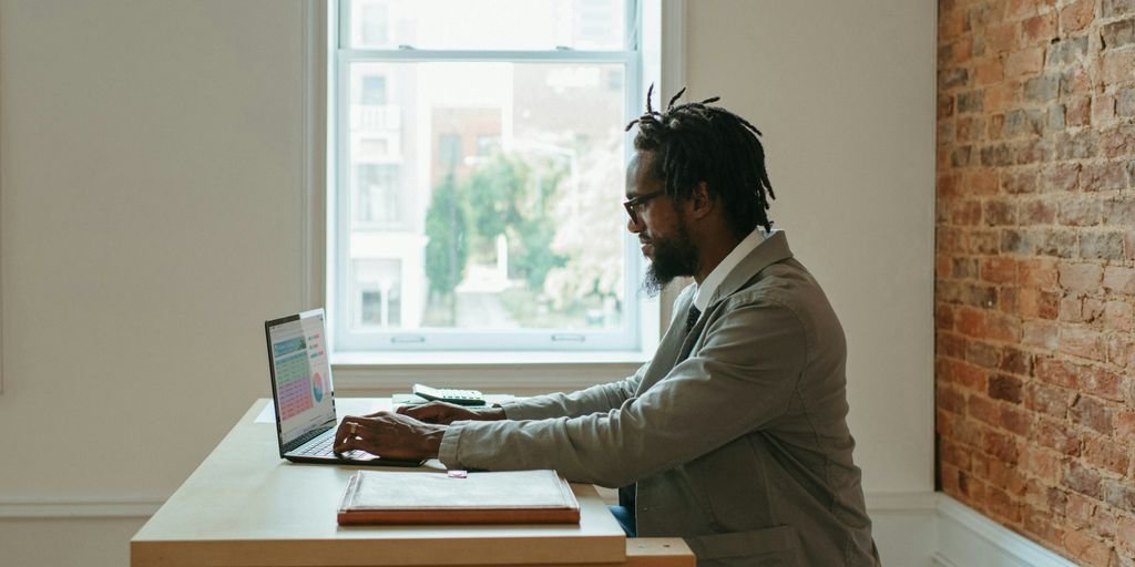 a person sitting at a desk with a laptop and papers