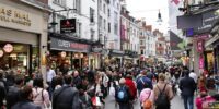 Crowded UK street with busy shoppers and markets.