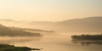 Tranquil landscape with hills and calm river in morning light.