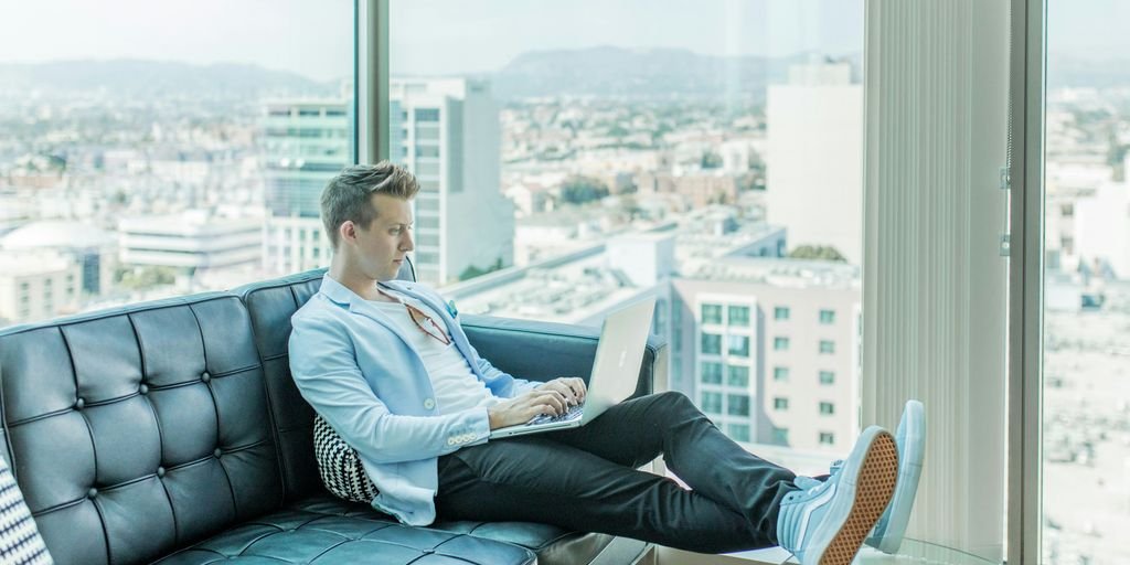 man sitting on sofa while using laptop